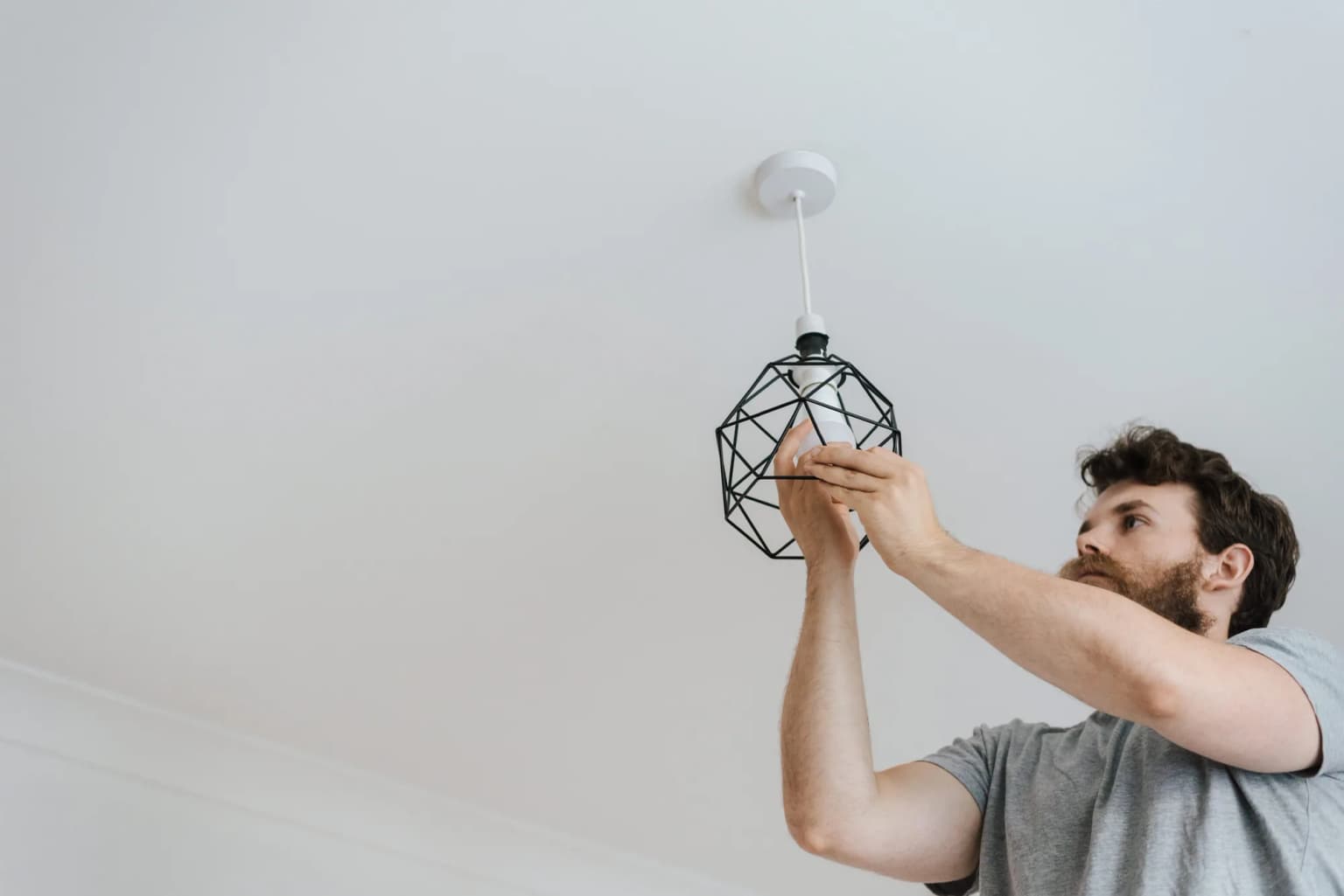 Person installing a modern geometric ceiling light in a residential room