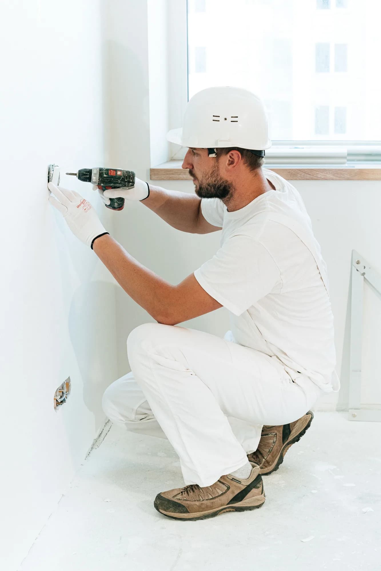 Electrical worker installing a wall outlet in a bright residential interior